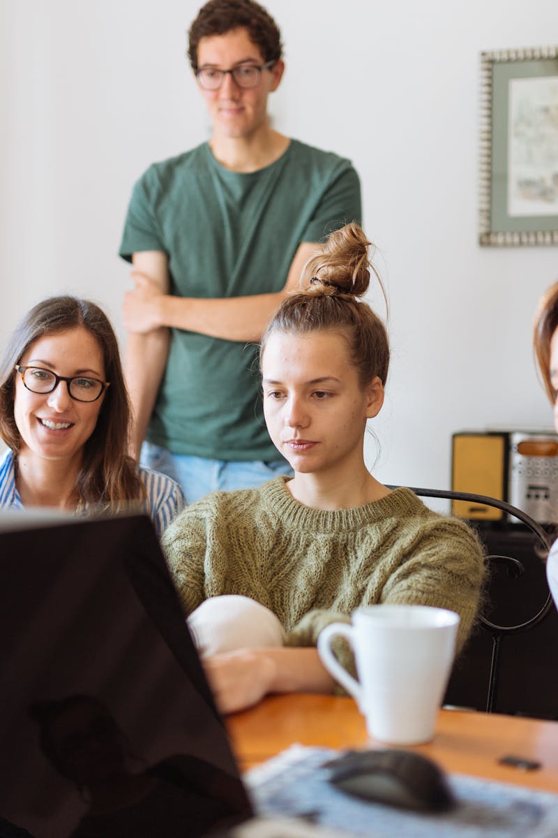 A diverse group of adults at work, enjoying a casual meeting indoors with focus and smiles.