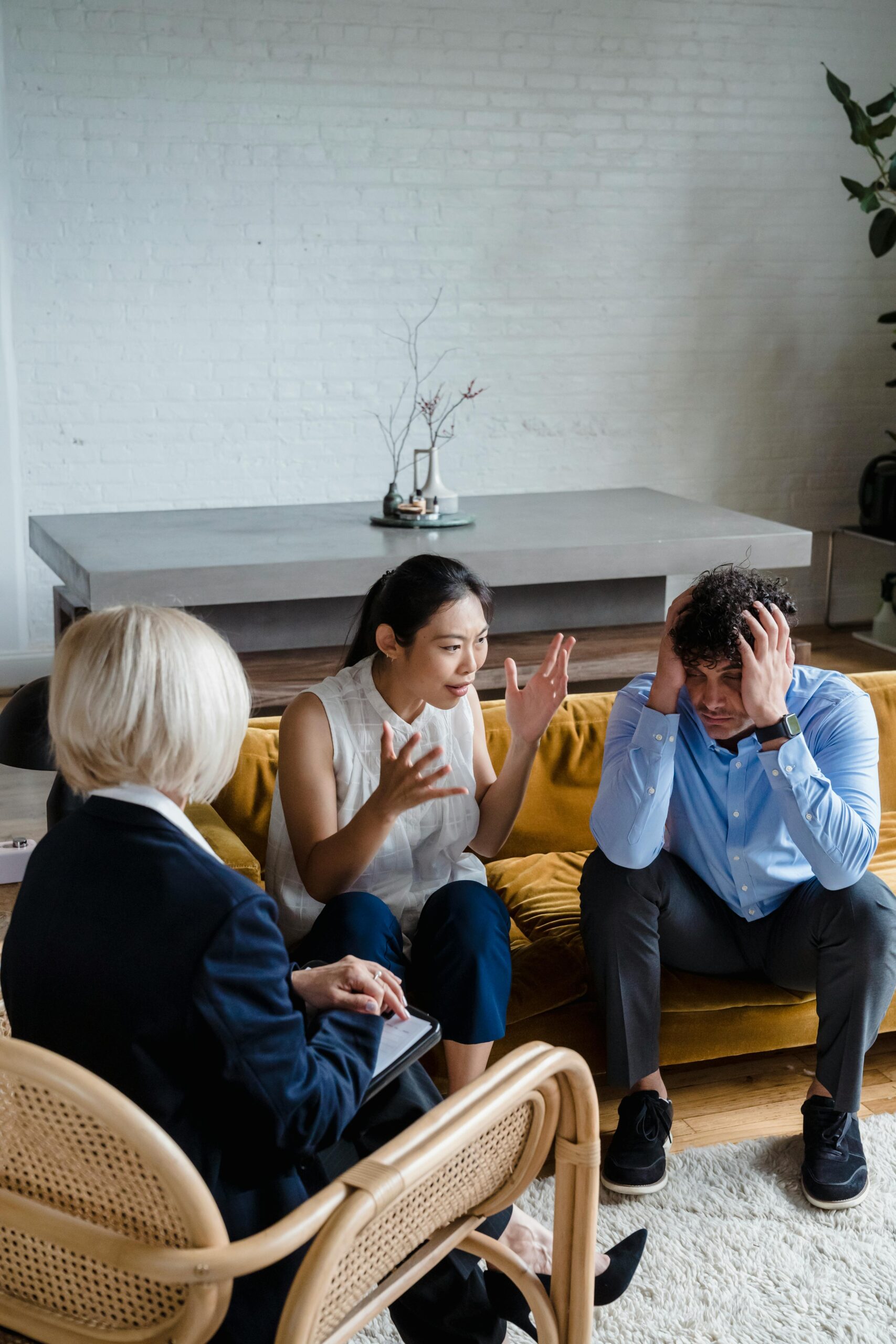 Couple engaged in an emotional counseling session with a therapist in an office setting.